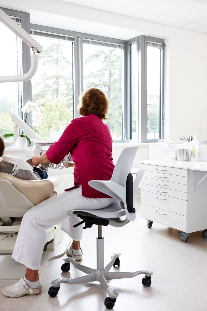 Dentist working on patient while seated on HAG Capisco chair