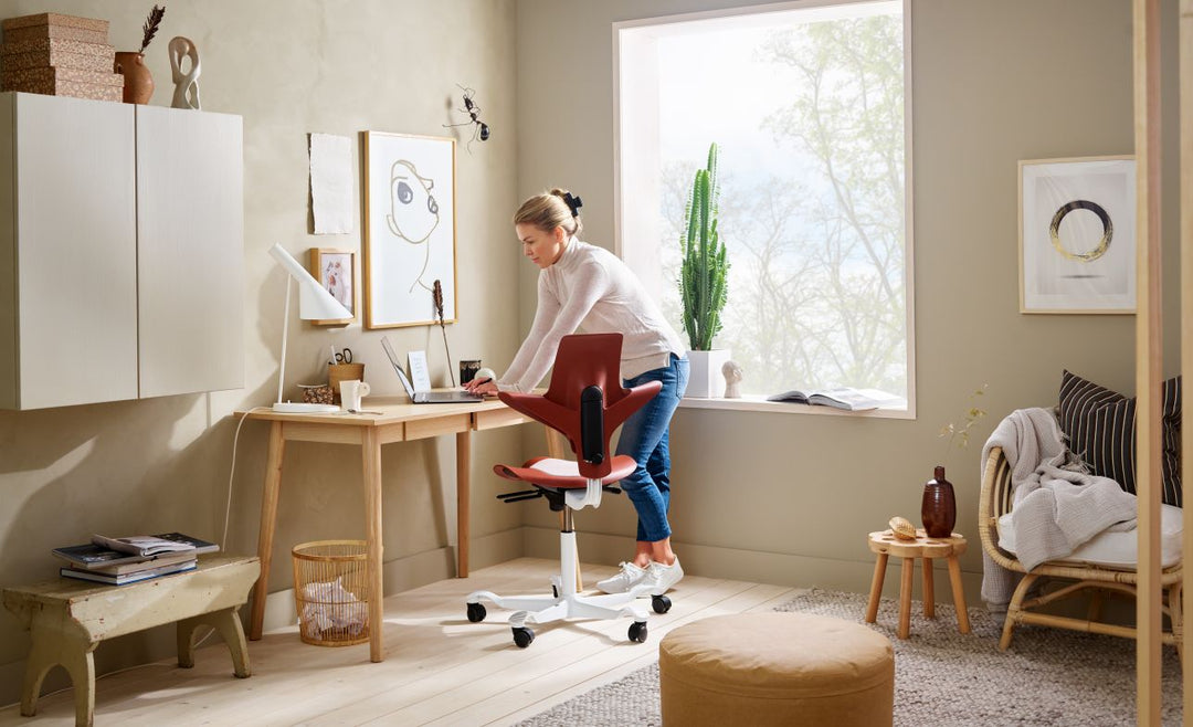HÅG Capisco Puls 8010 saddle chairs in a bright open workspace, shown at different seat heights