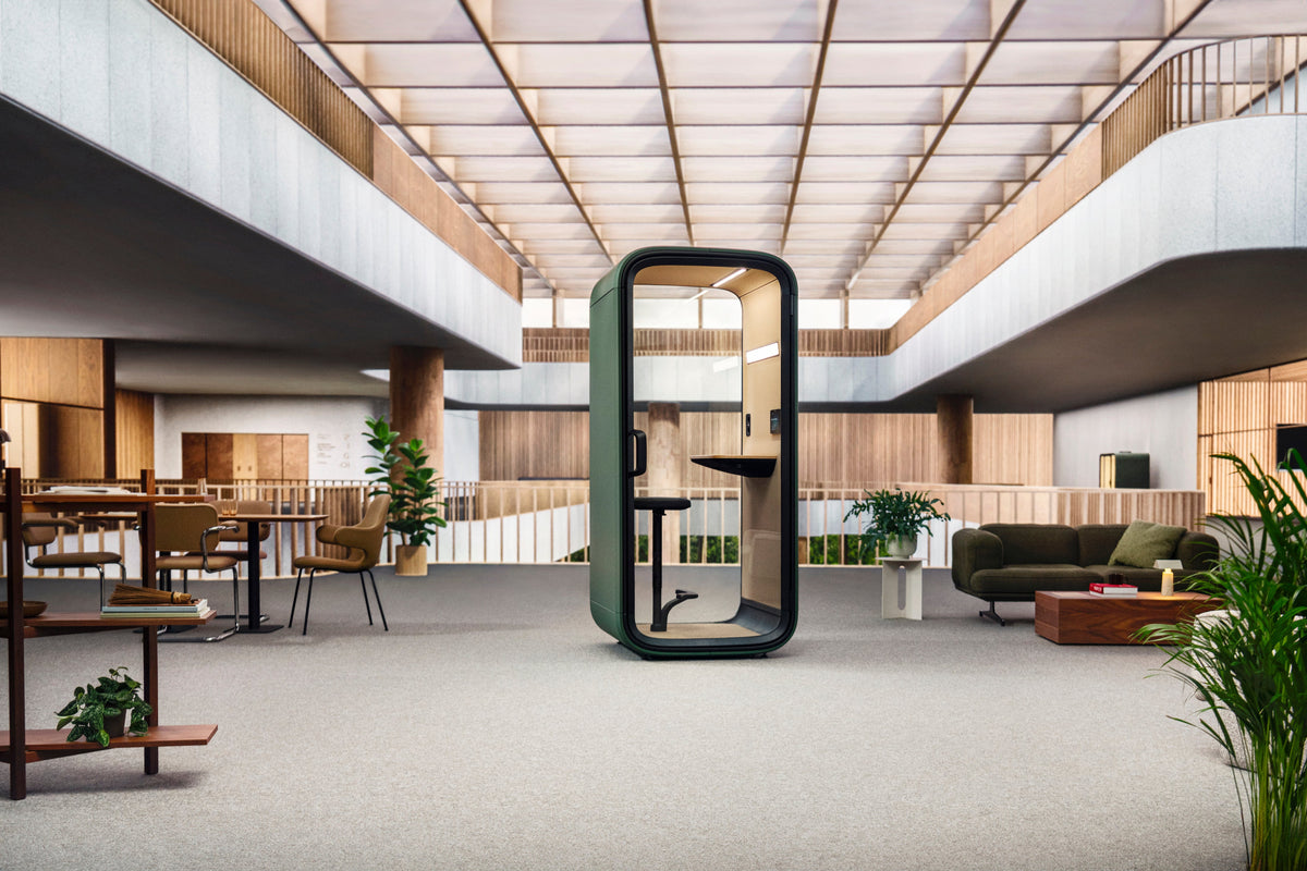 Framery One Compact phone booth with its door open on an open-plan office floor, positioned among desks where people are working