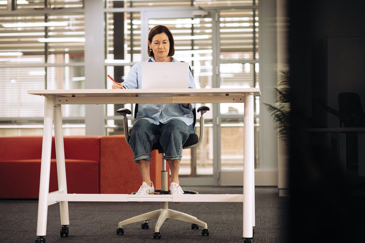 Woman seated on a light grey Buro Force drafting chair at a high table