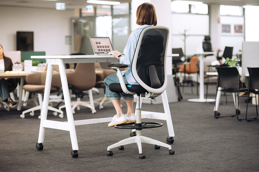 Light grey Buro Force drafting chair at a high table in an office, rear three-quarter view