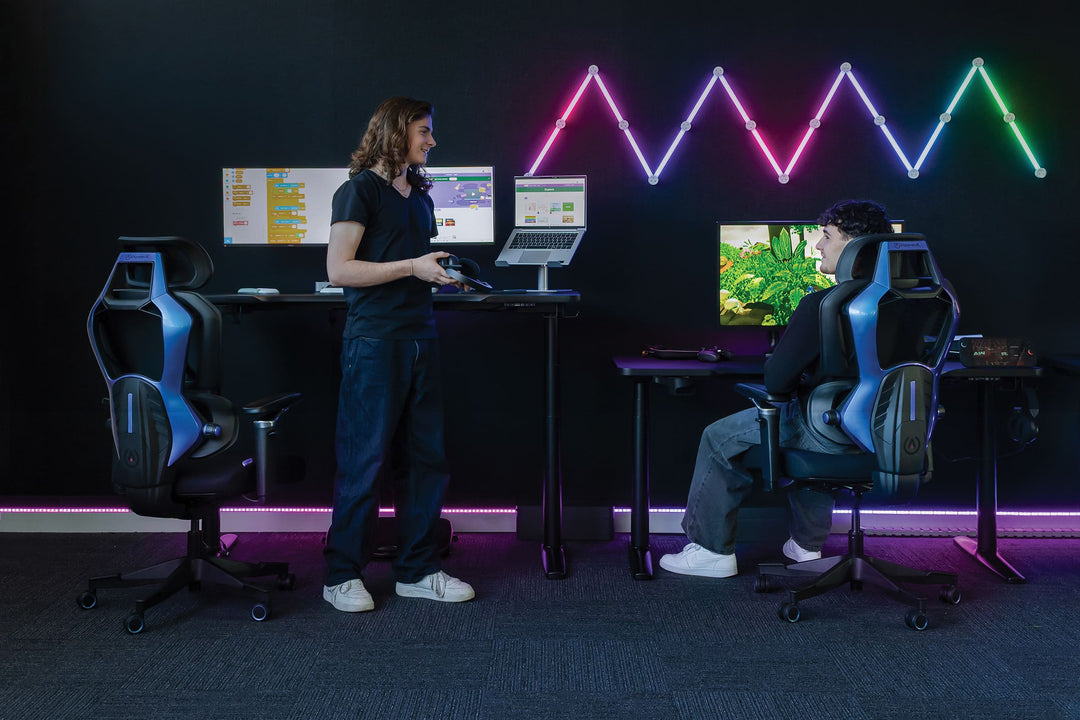 Buro x PowerA Frontier gaming desks in a gaming room, one raised to standing height and one at sitting height