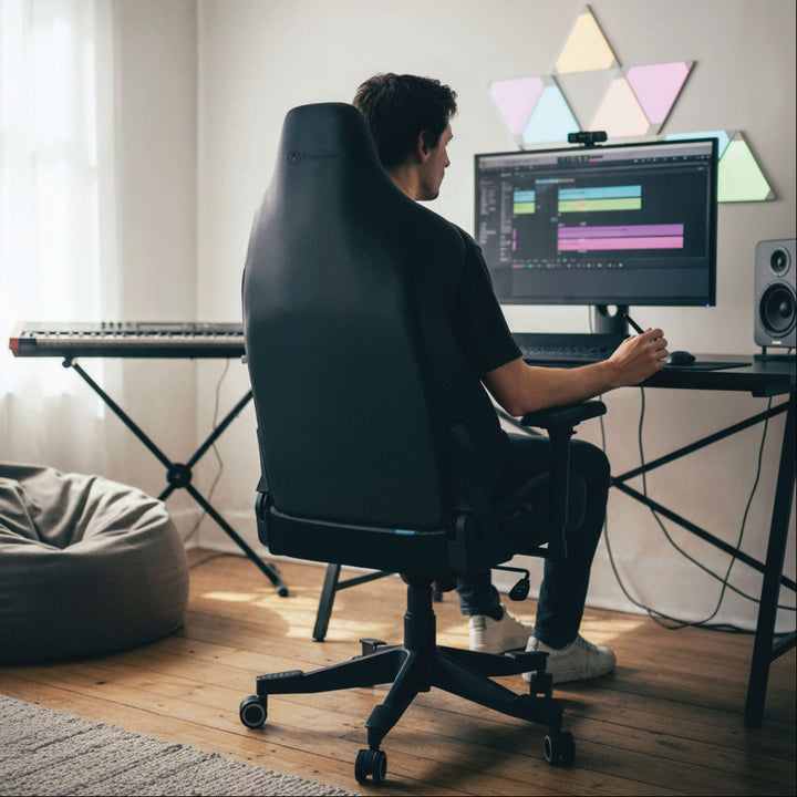 Man seated on a Buro x PowerA Navigator gaming chair at a desk, rear view
