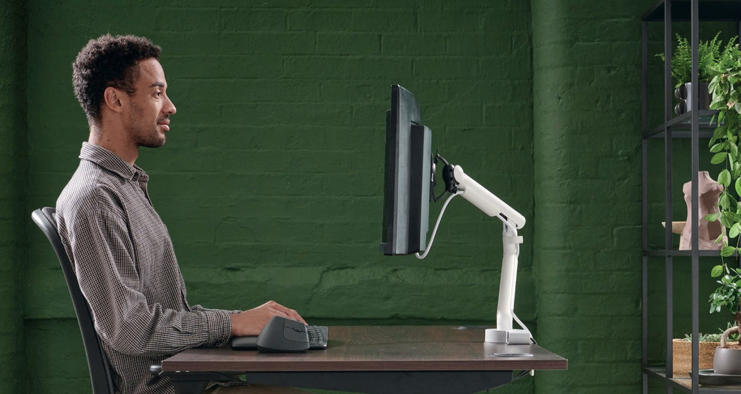 Man seated at a desk with his screen on a white CBS Flo monitor arm, green office - Chair Dinkum Australia