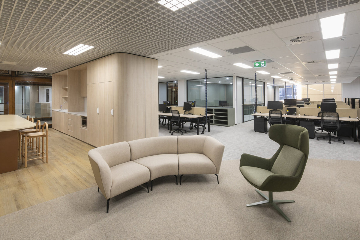 Curved sofa and olive swivel lounge chair beside the workstation floor in the Dymocks workplace on George Street, Sydney