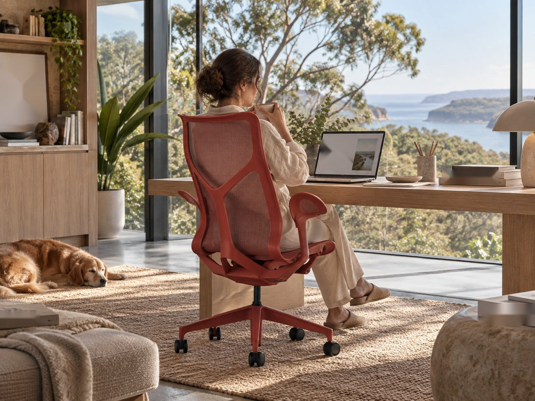 Herman Miller Cosm high back chair in Canyon with Leaf Arms, seen from behind with a woman seated at a timber desk by a window - Chair Dinkum Australia