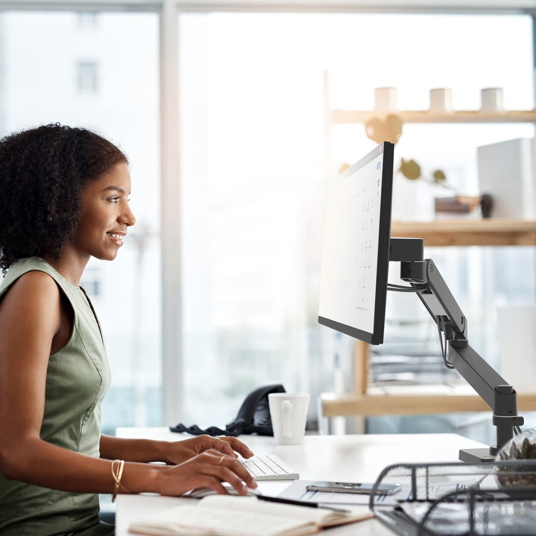 Woman working at a desk with her screen on an Ergotron LX Pro Desk Monitor Arm