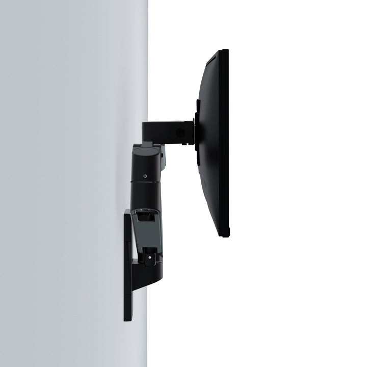 Matte black Ergotron LX Pro Wall Monitor Arm folded flat against a wall with the screen