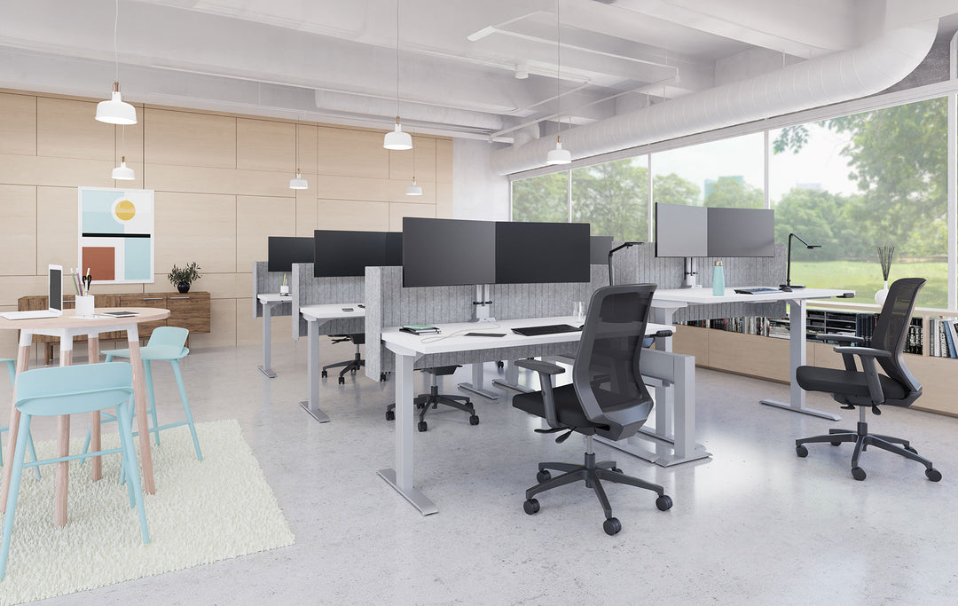Open office with HAT Collective E2 dual monitor arms in silver on height-adjustable desks