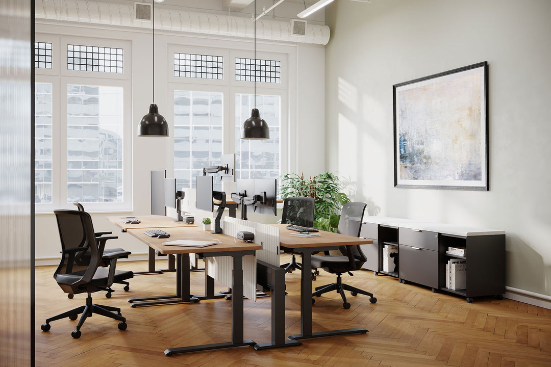 Open-plan office with HAT Collective E2 single and dual monitor arms in black on height-adjustable desks