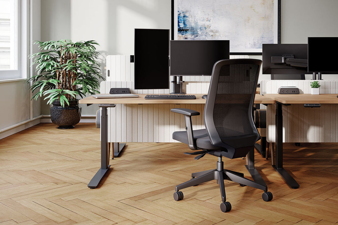 Height-adjustable desks with screens on black HAT Collective E2 monitor mounts, one screen turned to portrait