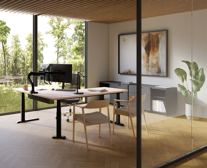 Private office overlooking a garden with a black HAT Collective E5 dual crossbar monitor arm on a height-adjustable desk