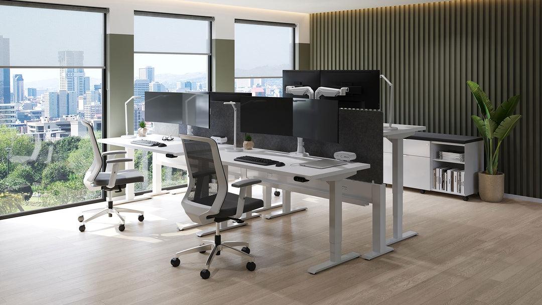 Open office with HAT Collective E5 dual monitor arms in a polished finish on height-adjustable desks