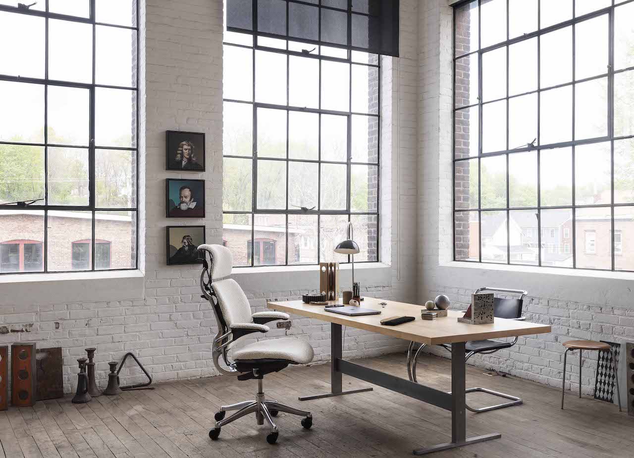 Humanscale Freedom chair in leather at a timber desk, shown from the side