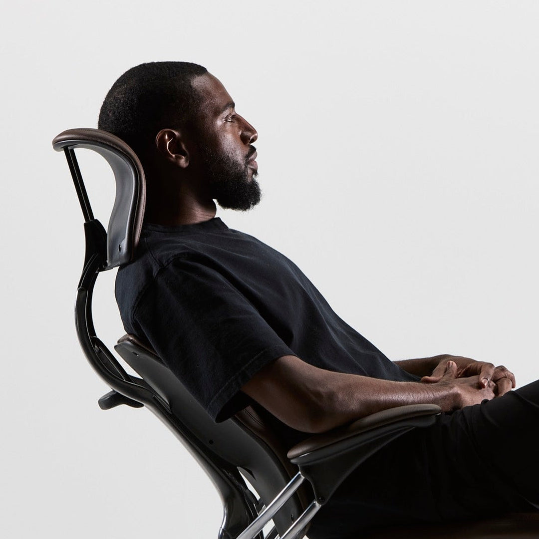 Man reclining in a Humanscale Freedom Headrest chair, side view, with the dynamic headrest supporting his head - Chair Dinkum Australia