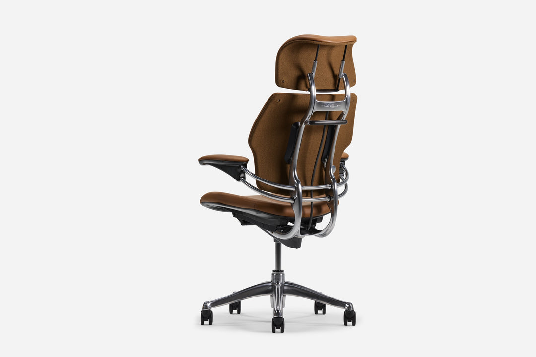 Rear three-quarter view of a Humanscale Freedom Headrest chair in brown leather showing the polished aluminium back frame and synchronous arms - Chair Dinkum Australia