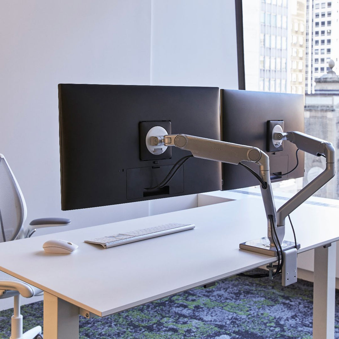 Two Humanscale M2.1 monitor arms carrying screens at an office desk (Humanscale photograph)