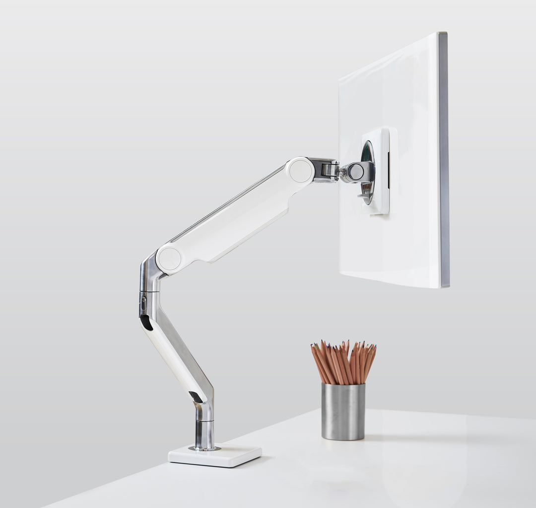 Humanscale M2.1 monitor arm in polished aluminium with white trim holding a monitor on a white desk with a desk clamp (Humanscale photograph)