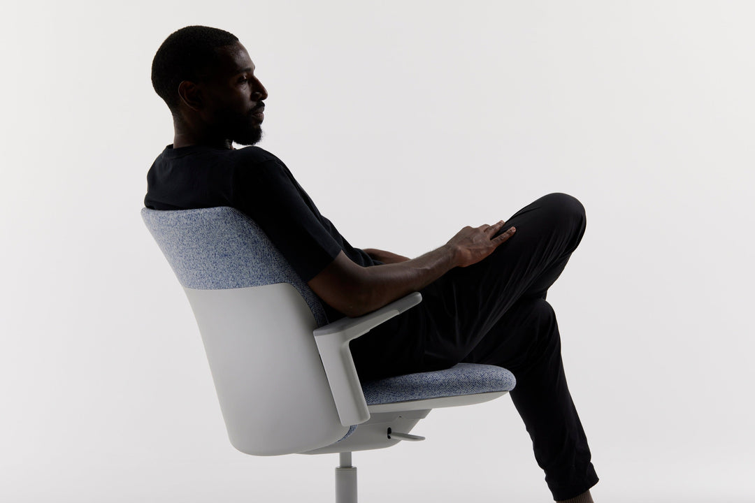 Man reclining in a Humanscale Path chair with a light grey frame and blue-grey knit back