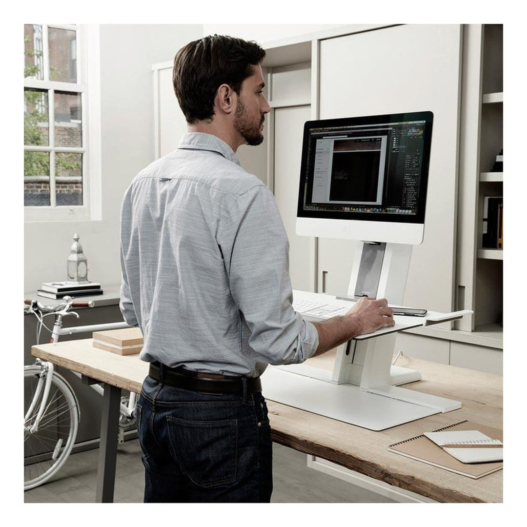 Man standing at a Humanscale QuickStand in white on a fixed-height desk - Humanscale photograph