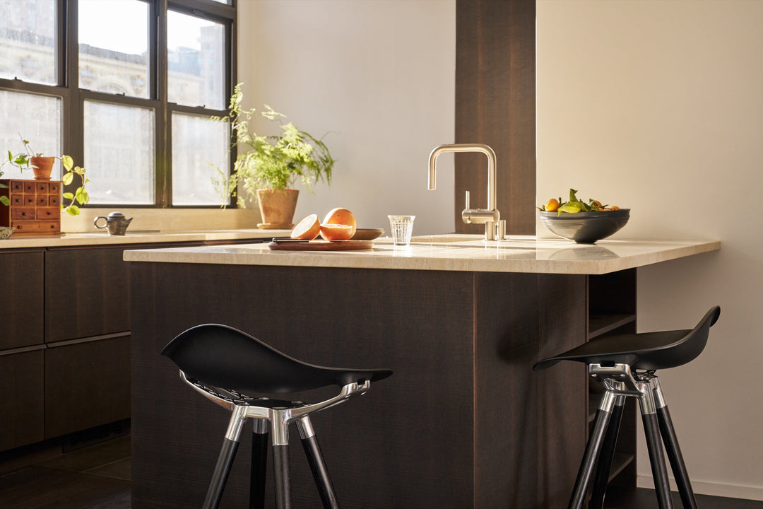 Two Humanscale Sedeo bar stools with dark oak legs, polished frames and black seats at a dark kitchen island