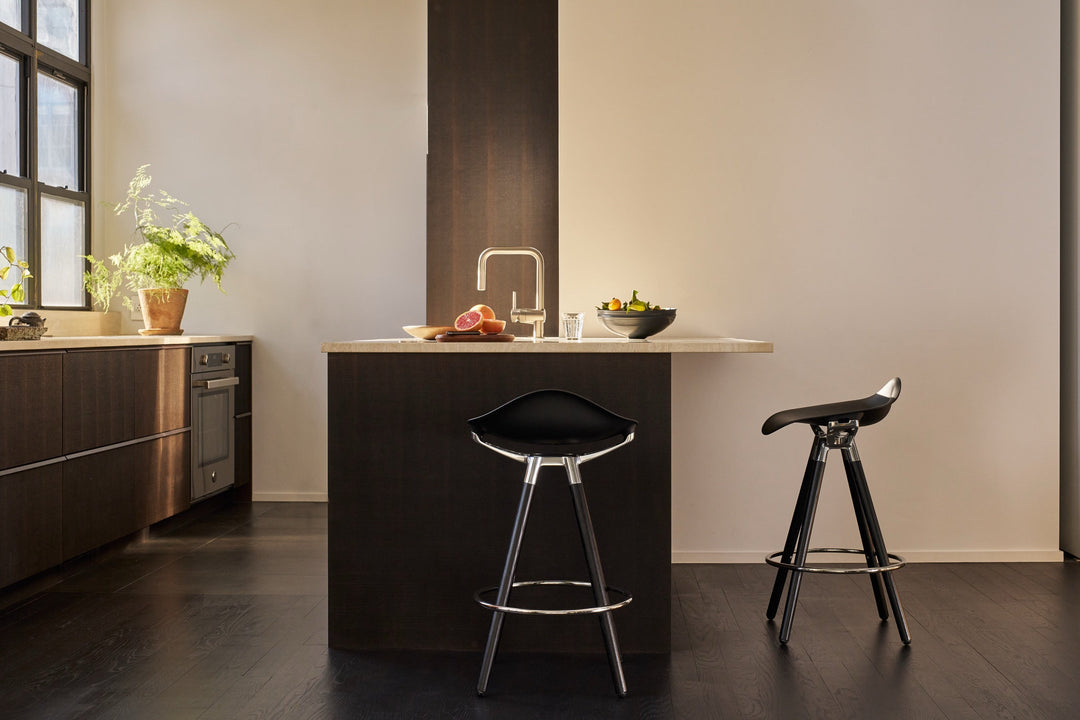 Humanscale Sedeo bar stools with black seats, dark oak legs and polished frames at a kitchen island in afternoon light