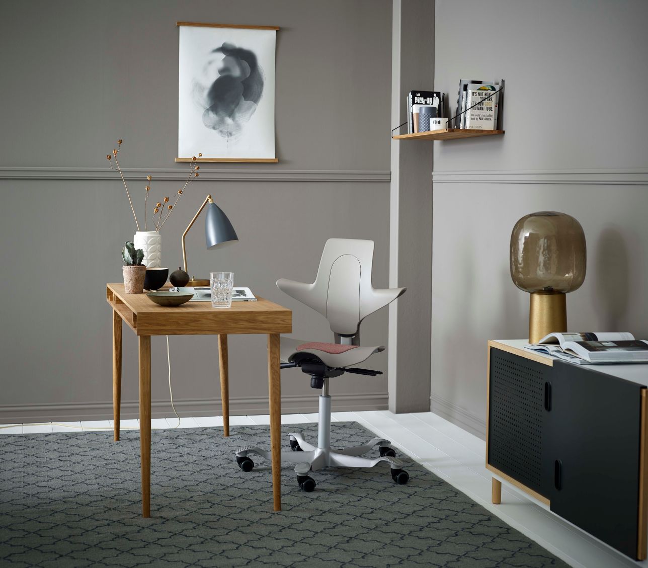 HÅG Capisco Puls in Clay at a low home desk, seat dropped near the bottom of its range with feet flat on the floor