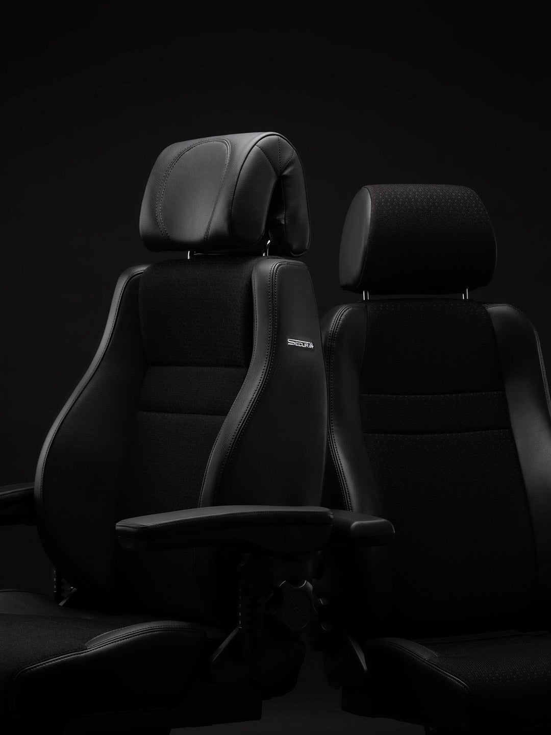 Two black RH Secur24 chairs in a dark studio, seen from the front three-quarter with headrests and padded armrests - Chair Dinkum Australia