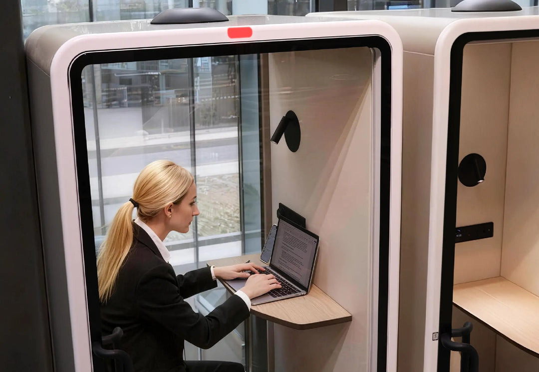 Woman working on a laptop at the fold-down desk inside a SoundBox VRT S booth - Chair Dinkum Australia