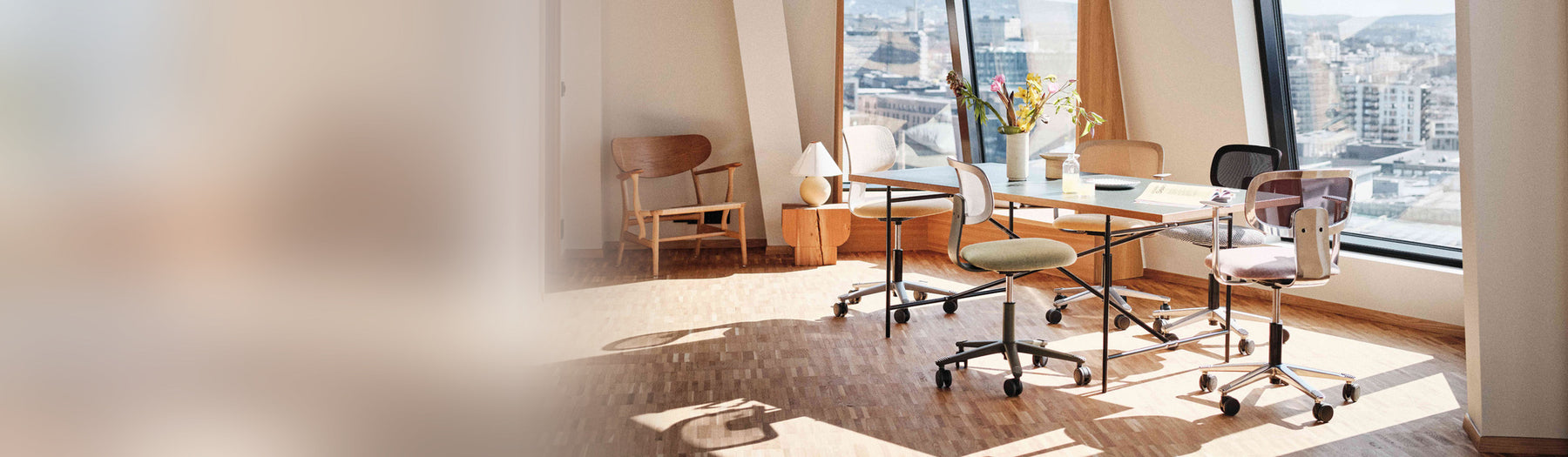 HÅG Tion Mesh task chairs around a meeting table in a sunlit corner office with city views
